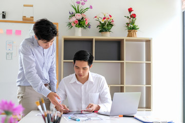 Wall Mural - two asian men are working together to design websites and application on mobile phone.