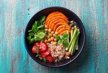 Wall Mural - Healthy vegetarian salad. Roasted pumpkin, quinoa, tomatoes, green salad. Buddha bowl. Blue wooden background. Top view.