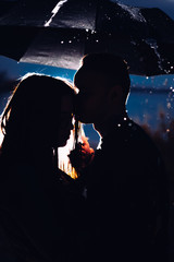 young man and woman under an umbrella and rain