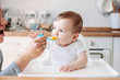 © Galina Zhigalova - Charming little baby boy 6-8 months eating first food pumpkin from spoon with mom at home