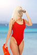 Pretty young blonde lifeguard in red sexy swimsuit with lifeguard rescue can floating buoy tubeon the white background Concept Woman in Swimsuite