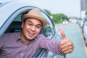 Young asian man showing thumbs up while driving car with copy space.