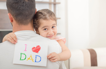 girl shows love dad card on her dad's shoulder