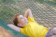 © EvgeniiAnd - boy lying in a hammock and dream. the child resting in the garden