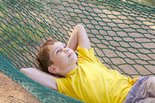 Boy Lying In A Hammock And Dream. The Child Resting In The Garden