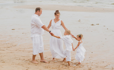 Wall Mural - Happy young family on the sunset at the beach.