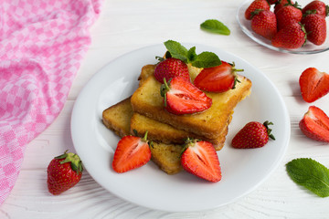 Wall Mural - French toasts with  strawberries and honey  in the white  plate on the white wooden background