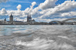 Kölner Dom, Groß St. Martin Kirche, Hohenzollernbrücke mit Blick über den Rhein mit altem römischen Pflaster im Vordergrund auf die Alstadt von Köln. Schwarz weiß Aufnahme mit blauem Himmel.