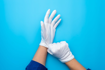 Two female hands wearing white gloves on blue background