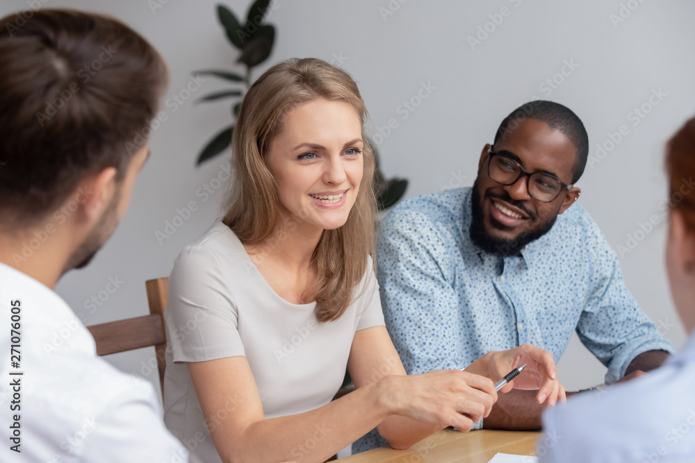 Happy smiling young woman talking with coworkers at work