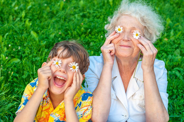 happy grandmother and laughing grandchild fooling around the law of putting chamomiles instead of ey