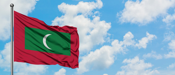 Maldives flag waving in the wind against white cloudy blue sky. Diplomacy concept, international relations.