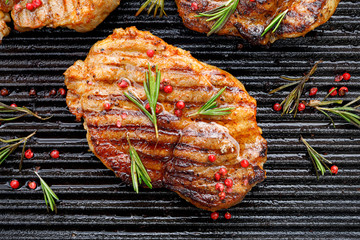 Wall Mural - Grilled pork steak, pork neck with the addition of herbs and spices on the grill plate, top view, Grilled meat, bbq, barbecue grill