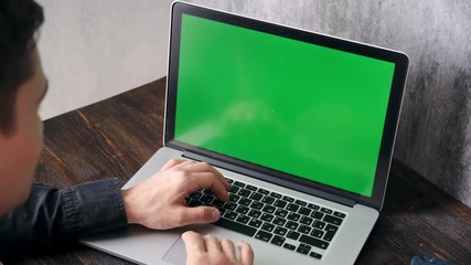 young programmer at work. businessman in the workplace. freelancer for the computer. The manager works on a laptop. green screen chroma key for. Laptop close-up with hands. man typing on a laptop
