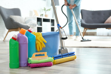 Wall Mural - Detergents, bucket and mop on floor with janitor vacuuming carpet indoors