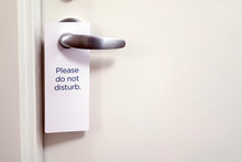 Closed White Door Of Hotel Room With Please Do Not Disturb Sign