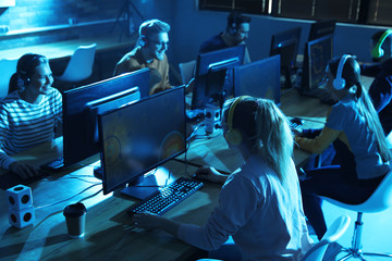 Wall Mural - Group of people playing video games in internet cafe