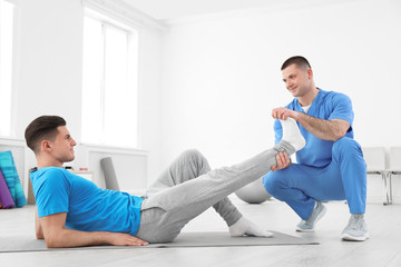 Canvas Print - Professional physiotherapist working with male patient in rehabilitation center