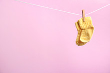 Small Socks Hanging On Washing Line Against Color Background, Space For Text. Baby Accessories