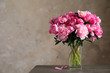 Fragrant peonies in vase on table against color background, space for text. Beautiful spring flowers