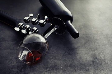 Guitar and high glass with red wine on a stone background.