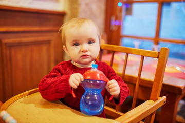 Wall Mural - Little baby girl sitting in high chair at home or at restaurant