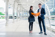 © shutterdemon - Asian businesswoman holding document file on hand and talk about business plan with Caucasian businessman in the city. wihe copy space for text