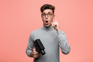 Wall Mural - Young intellectual man holding a film camera having some great idea, concept of creativity.