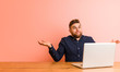 © Asier - Young man working with his laptop doubting and shrugging him shoulders in questioning gesture.