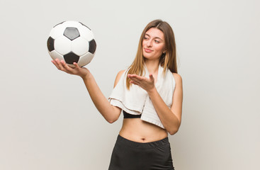 Wall Mural - Young fitness russian woman holding something with hand. Holding a soccer ball.