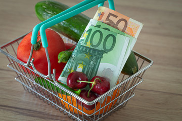 vegetables and fruits in the shopping basket along with Euro money / the concept of food price increase