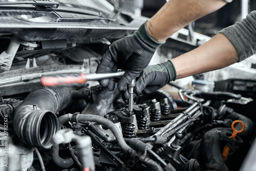 Fotografía Close up of man's hands using wrench to remove spark plugs