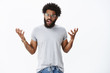 © Cookie Studio - Disappointed customer arguing being pissed with service. Portrait of displeased angry young african american man in glasses with tattoos and piercing shrugging with raised hands in confusion and anger