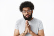 © Cookie Studio - Close-up shot of gloomy and silly african american bearded boyfriend with pierced nose holding hands in pray making moody and upset expression as begging cook favorite meal for dinner