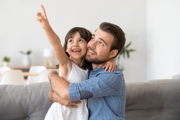 Canvas Print - Happy cute daughter show something to smiling young dad