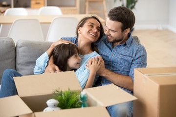 Smiling parents relax with daughter on home couch