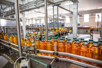 Wall Mural - Plastic bottles with juice on automated conveyor line or belt in modern beverage plant or factory production