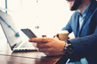 © Alex from the Rock - Close-up of businessman working in city cafe. Wearing suit, stubble and texting on mobile phone. With laptop and stats on the table