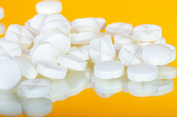 Wall Mural - various white pills on a yellow mirror glass background