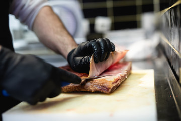 Wall Mural - Butcher cutting meat at counter in butchery.