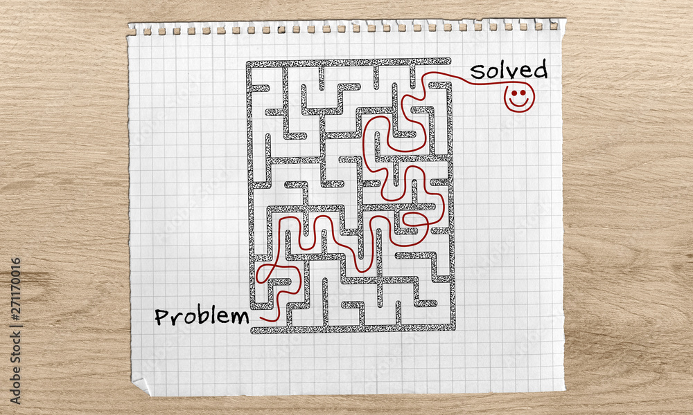 Problem Solving maze, Problem Solved text, maze solution hand drawn on with red marker on graph paper over wooden desk from problem to solution, horizontal view