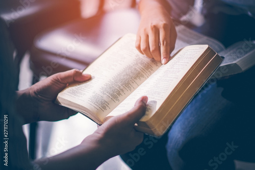 Fotomural Male adults are reading the Holy bible by pointing to the character and to share the gospel to youth