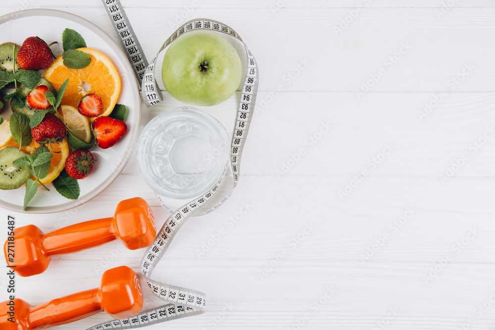 Diet plan, menu or program, tape measure, water, dumbbells and diet food of fresh fruits on white background, weight loss and detox concept, top view - obrazy, fototapety, plakaty 