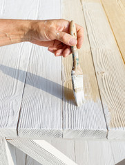 Wall Mural - Worker painting white wooden furniture outdoor.