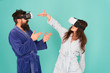 © be free - Hands up. Stand and deliver. VR technology and future. VR communication. Exciting impressions. Couple in bathrobes wear VR glasses. Gaming and entertainment. Man and woman explore VR at home