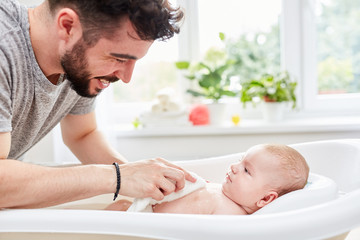 vater wäscht sein baby mit dem waschlappen