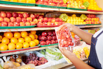 Package of strawberries in hands of female grocery store customer