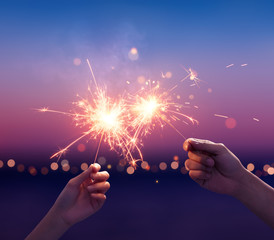 Wall Mural - Couple holding a sparklers on the beach