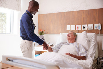 Wall Mural - Doctor Shaking Hands With Senior Male Patient In Hospital Bed In Geriatric Unit