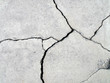 © andy0man - detail of fractured concrete sidewalk floor, gray grunge cement surface with large cracks, earthquake effect causes ground and building wall to damaged, abstract texture background, close up top view